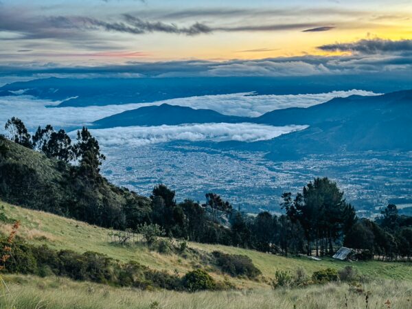 Imbabura Volcano features a breathtaking view of the city below, with rolling hills and clouds at sunset in Ecuador.