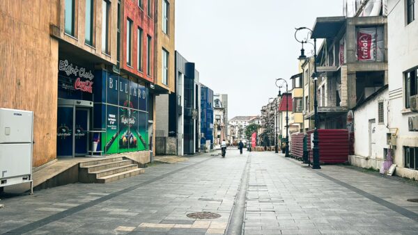 Vibrant street scene with modern buildings and shops in the old town area of Craiova, Romania, under a cloudy sky.