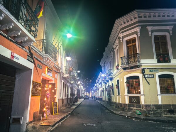 Vibrant street scene at night in San Marcos, Quito, Ecuador, featuring colorful lights and classic colonial architecture.