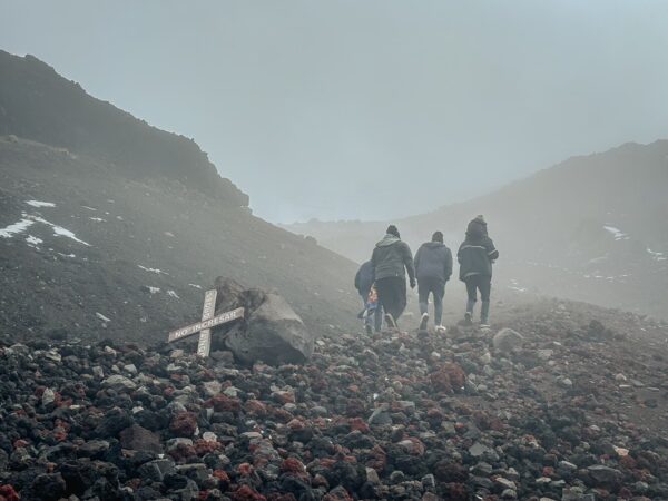 Hikers navigate rocky terrain shrouded in mist near the José Rivas Refuge, Mount Cotopaxi, Ecuador.