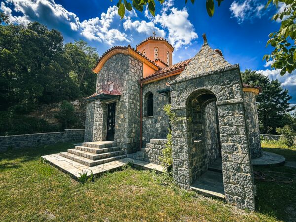 Panagia Kernitsis Monastery features stone architecture and vibrant orange roofs, surrounded by greenery in Arcadia, Greece.