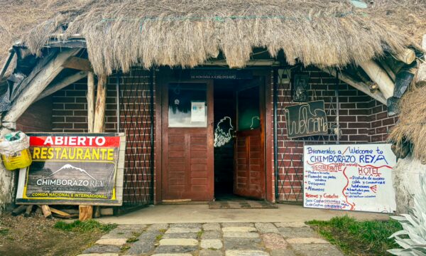 Rey Venture Restaurant Lodge features a rustic entrance with thatched roof, inviting signs in Machachi, Ecuador, near Chimborazo.