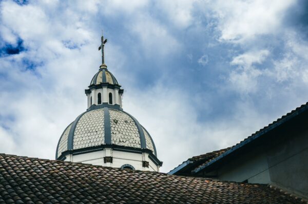 Dome topped with a cross against a cloudy sky, highlighting the architectural beauty of Ibarra, Ecuador.