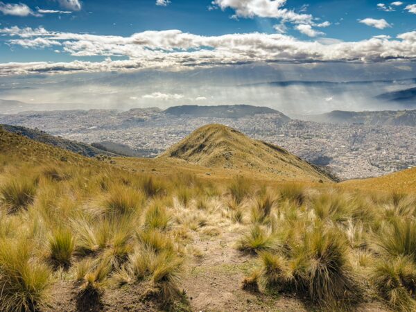 Pichincha Volcano offers panoramic views of the sprawling city below, surrounded by lush, green hills and dramatic cloud formations.
