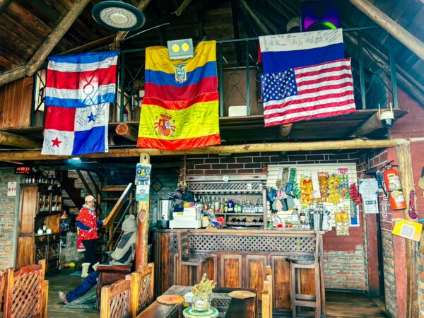 Traditional wooden interior of Rey Venture Restaurant Lodge in Machachi, Ecuador, adorned with flags and local decor.