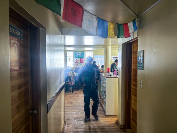 Colorful prayer flags hang in a cozy hallway leading to a dining area at Refugio Carrel, near Chimborazo Volcano, Ecuador.