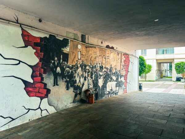 Historical mural depicting people on a cracked wall in the Old Town of Craiova, Romania, surrounded by modern architecture.