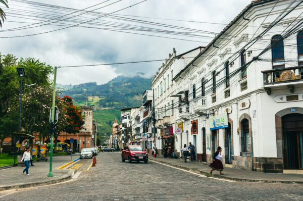 Vibrant streets of Parque La Merced in Ibarra, Ecuador, lined with colorful buildings and lush green hills in the background.