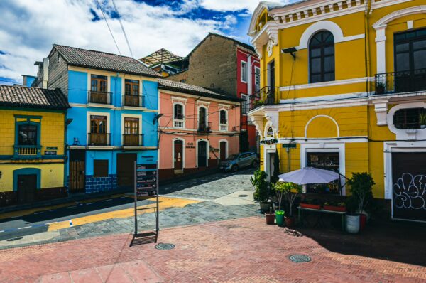 Vibrant streets of Quito, Ecuador, showcase colorful colonial buildings and a lively atmosphere under a bright blue sky.