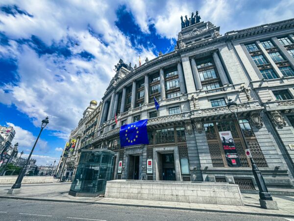 Historic architecture showcases ornate details, with a prominent European Union flag flying in front in Madrid, Spain.