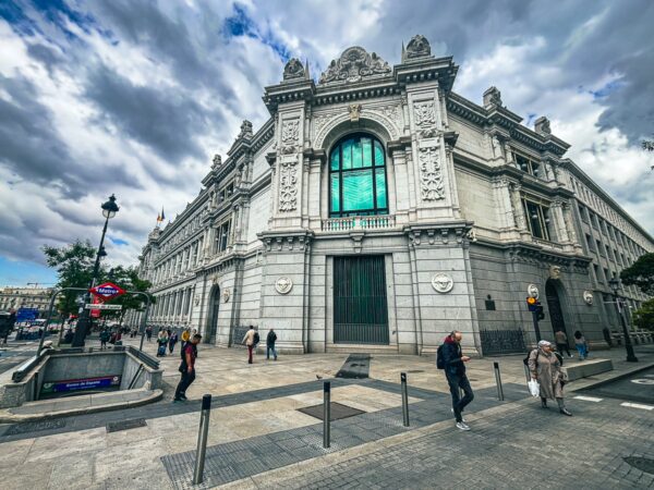 ornate architecture and green-tinted windows of a historic building in Madrid, Spain, under a cloudy sky.