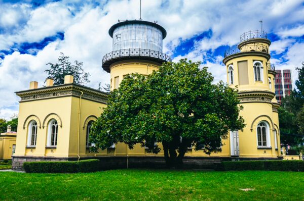Observatorio Astronómico features a historic yellow building with a glass dome, surrounded by lush greenery in Quito, Ecuador.