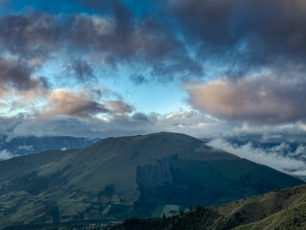 Majestic Imbabura Volcano rises under a stunning blue sky with clouds, surrounded by lush green landscapes in Ecuador.