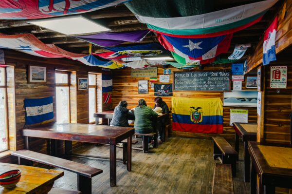 Cozy interior of the José Rivas Refuge decorated with colorful flags and wooden tables, Mount Cotopaxi, Ecuador.