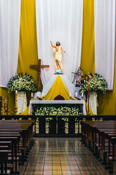 Vibrant altar of La Merced Church in Ibarra, Ecuador, featuring flowers, a statue of Jesus, and golden drapes.