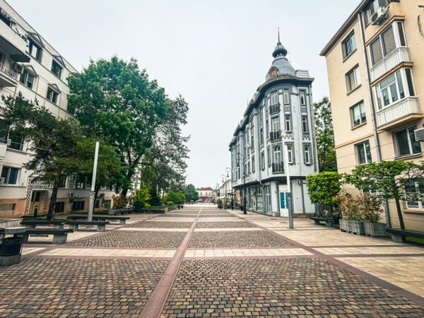 Cobblestone street lined with greenery and distinctive architecture in the Old Town of Craiova, Romania.