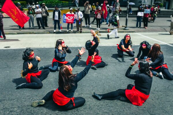 Celebratory dancers in black and red costumes perform during the International Workers' Day parade in Quito, Ecuador.