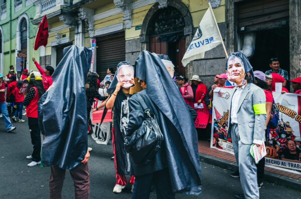 Participants in the International Workers’ Day parade in Quito, Ecuador, wear masks and carry banners, celebrating in vibrant attire.