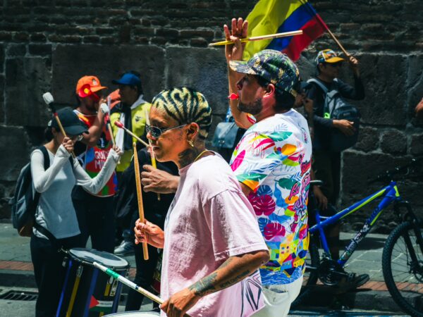 Vibrant parade celebrating International Workers' Day in Quito, Ecuador, with participants holding flags and musical instruments.