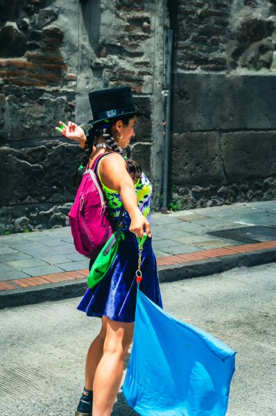 Vibrant celebration at the International Workers' Day parade in Quito, Ecuador, featuring a woman in colorful attire waving a blue flag.