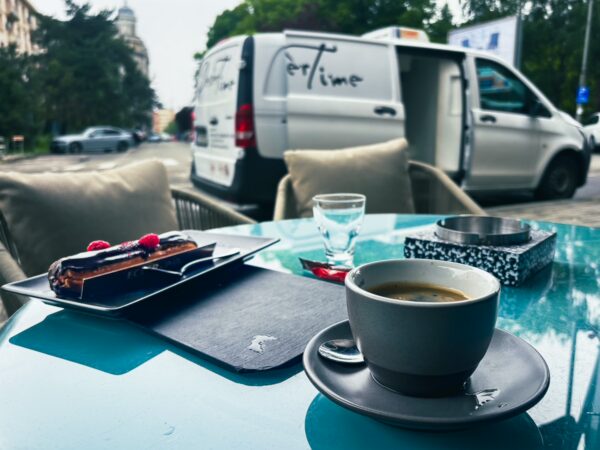 Rich espresso and dessert rest on a turquoise table, with a van in the background in Craiova, Romania's vibrant atmosphere.