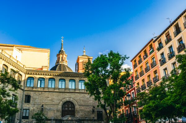 Beautiful architecture featuring domed rooftops and colorful buildings under a clear blue sky in Madrid, Spain.