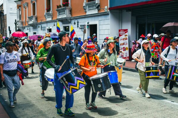 Colorful drummers in vibrant outfits march in the International Workers' Day parade through the streets of Quito, Ecuador, 2026.