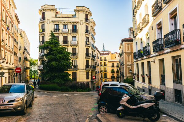 Charming street scene featuring vintage buildings and greenery under bright skies in Madrid, Spain.