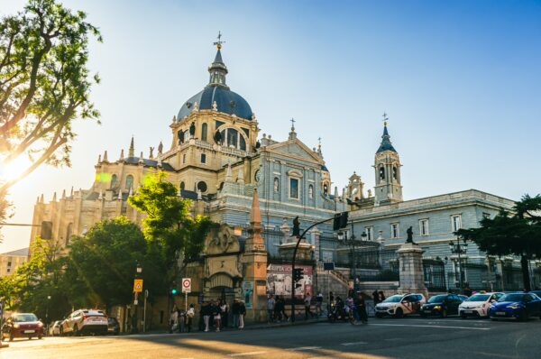 Stunning sunset illuminates the grand dome and ornate architecture of the Almudena Cathedral in Madrid, Spain.
