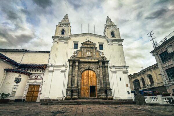 Stunning facade of Iglesia Cermen Alto in Quito, Ecuador, showcasing colonial architecture with ornate stone details and a grand wooden door.