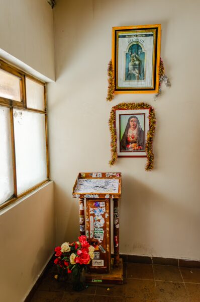 Colorful shrine with framed religious images and fresh flowers at Jose Rivas Refuge, Mount Cotopaxi, Ecuador.