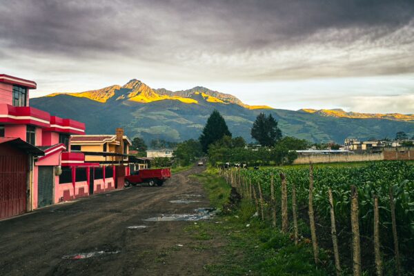 Raminahui Volcano rises in the background, flanked by lush fields and colorful buildings in Machachi, Ecuador.