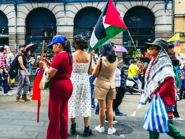 Celebrants in vibrant attire hold flags during the International Workers' Day parade in Quito, Ecuador, showcasing cultural diversity.