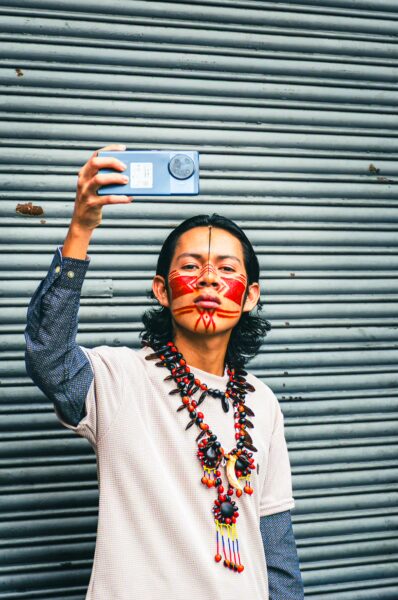 Brightly dressed participant with traditional face paint and jewelry takes a selfie during the International Workers' Day parade in Quito, Ecuador.