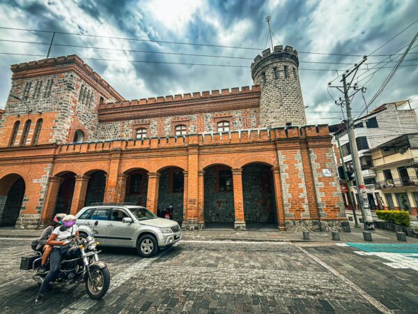 Centro Cultural El Cuartel features striking stone architecture and vibrant orange accents, set against a moody sky in Ibarra, Ecuador.