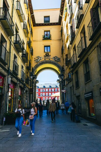 Bustling Plaza Mayor in Madrid, Spain, framed by vibrant buildings and archways, with pedestrians enjoying the lively atmosphere.