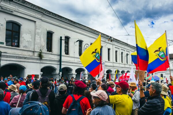 Colorful Ecuadorian flags wave among a crowd celebrating International Workers' Day in Quito, highlighting vibrant unity and festivity.
