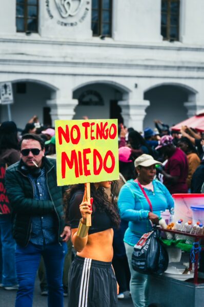 Vibrant International Workers' Day parade in Quito, Ecuador, featuring a participant holding a bold yellow sign that reads "No Tengo Miedo."