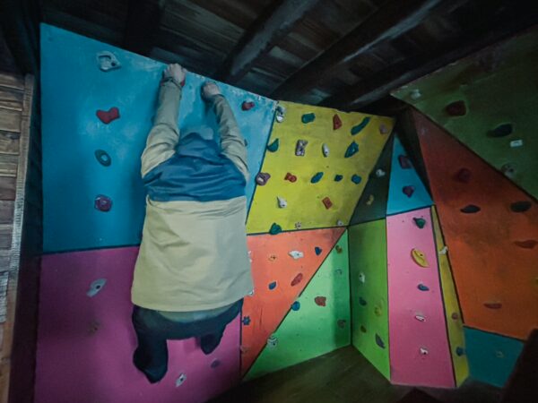 Climber navigating colorful rock climbing walls inside the José Rivas Refuge, showcasing vibrant colors and dynamic angles at Mount Cotopaxi, Ecuador.