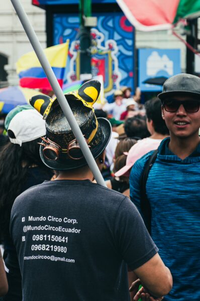 Crowds celebrate International Workers' Day in Quito, Ecuador, featuring colorful flags and festive attire.