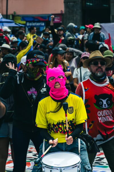 Vibrant International Workers' Day parade in Quito, Ecuador, featuring participants in colorful attire and masks, celebrating unity and activism.