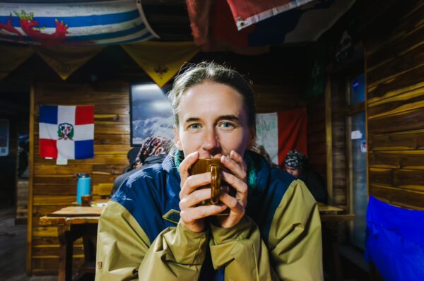 Warm drink enjoyed inside the cozy José Rivas Refuge at Mount Cotopaxi, Ecuador, surrounded by colorful flags and rustic wooden decor.