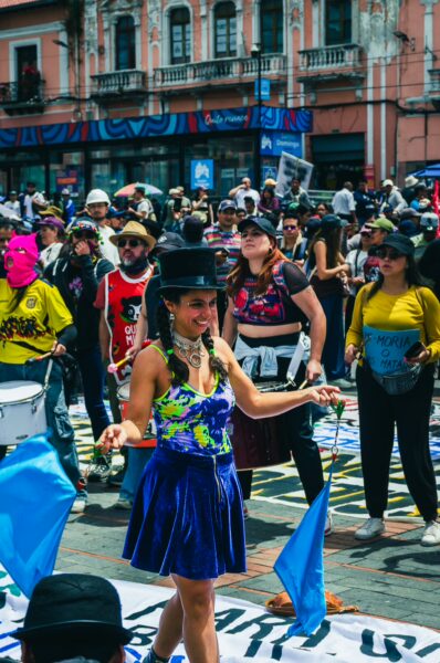 Colorful parade participants joyfully celebrate International Workers' Day in Quito, Ecuador, wearing vibrant costumes and hats.