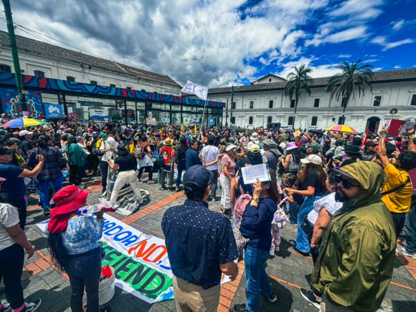 Vibrant scene of the International Workers' Day parade in Quito, Ecuador, featuring crowds, banners, and festive colors.