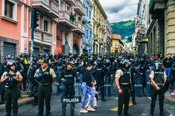 Crowd of police in riot gear stands ready in the streets of Quito, Ecuador, during the International Workers' Day parade.