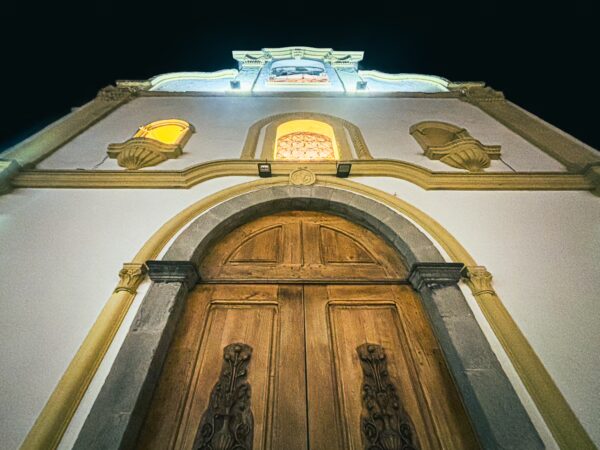 San Marcos Church features intricate wooden doors and illuminated details at night, showcasing its architectural beauty in Quito, Ecuador.