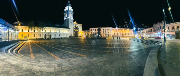 Plaza Santo Domingo features elegant colonial architecture and a striking clock tower, illuminated at night in Quito, Ecuador.