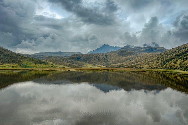 Laguna de Limpiopungo reflects stunning mountains and dramatic skies in Cotopaxi National Park, Ecuador, showcasing serene natural beauty.