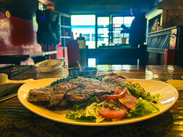Succulent grilled steak served with a fresh salad and dipping sauce at Asadero El Rinconcito in Machachi, Ecuador.