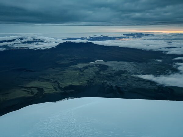 Majestic views from Mount Cotopaxi showcasing snow-covered peaks and rolling clouds over the lush Ecuadorian landscape.